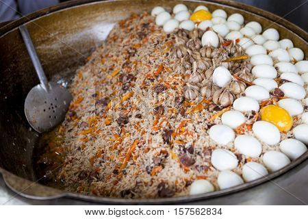 Traditional Asian pilaf with beef and chicken eggs. A large cauldron, rice devzira, cumin spices, cotton seed oil. The famous dish of the East