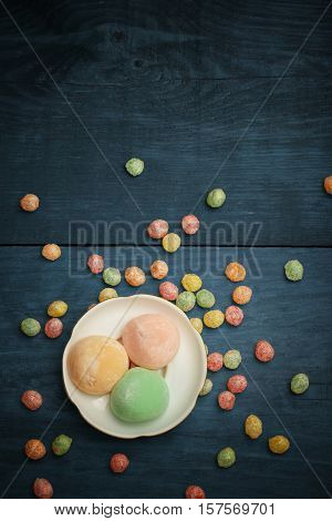 Mochi Rice Cakes In White Plate With Colorful Fruit Candy Drops At Wooden Background
