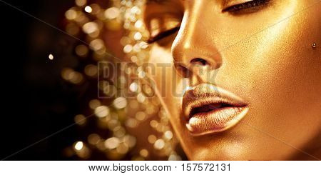 Fashion art Golden skin Woman face portrait closeup. Beauty gold eyes, Lips and Skin. Model girl. Glamour shiny professional makeup