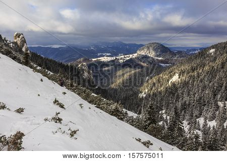 Winter mountains with snow and forests in cloudy day.