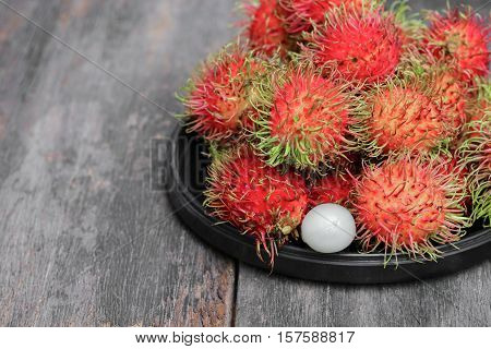 rambutan sweet fruit fresh in plate on wood background : Select focus with shallow depth of field.