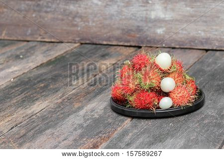 rambutan sweet fruit fresh in plate on wood background : Select focus with shallow depth of field.