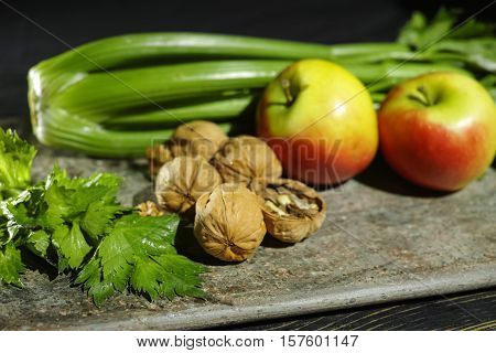 Ingredients for Waldorf salad - celery apples walnuts - fresh and healthy vegetables on granite board.