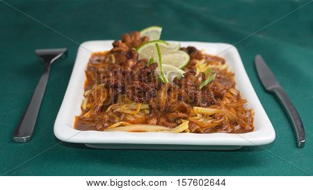 Grilled octopus with potatoes and paprika sauce on a dark green background
