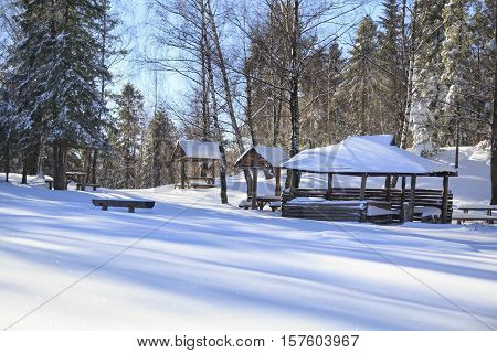 Winter landscape with infact snow in the forest with several wooden tables and an aclove