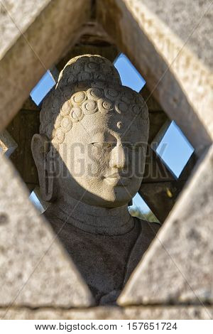 Carved stone buddha statue inside small stupa