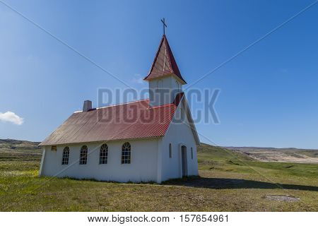 Little church with red roof on the beach at Breidavik on Iceland with the ocean mountains and meadows.