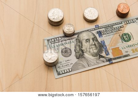 A hundred dollar bill surrounded by a stack of coins
