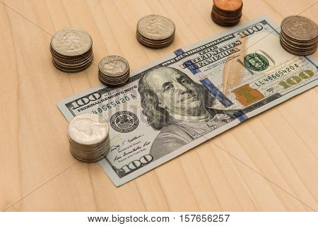 A hundred dollar bill surrounded by a stack of coins