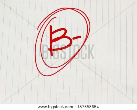 B minus (B-) grade written in red on notebook paper