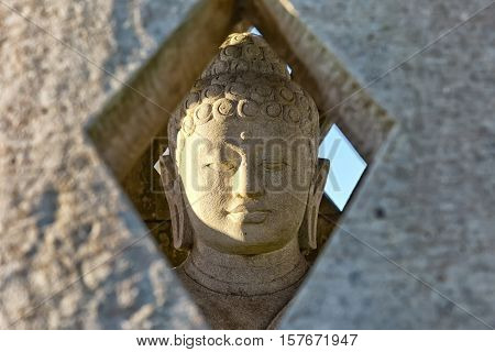 Carved stone buddha statue inside small stupa. Frontal view