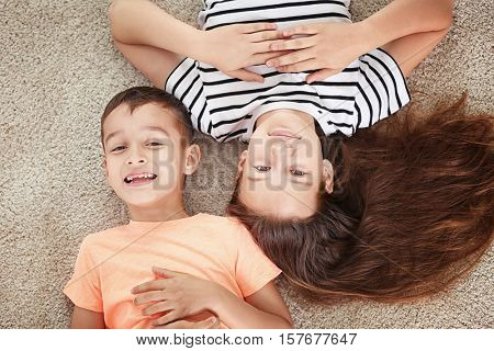 Brother and sister lying on carpet