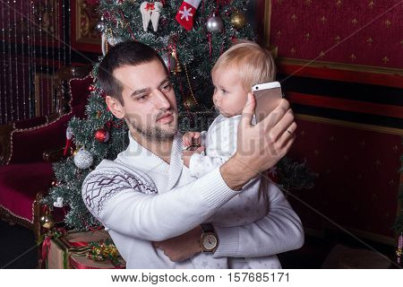 selfie in Christmas. happy family father dad playing with baby daughter and photographed on a mobile phone