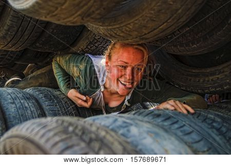 Tyumen, Russia - June 11, 2016: Race of Heroes project on the ground of the highest military and engineering school. Woman moves between old tires. Born again stage