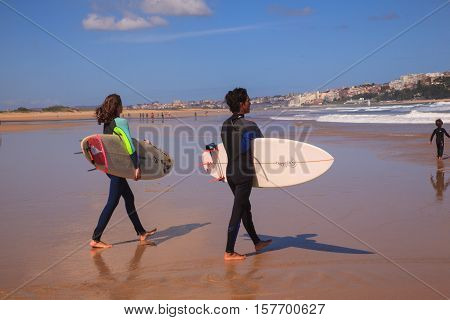 SANTANDER SPAIN - AUGUST 20: Surfer couple carrying their surfboard on the beach on August 20 2016