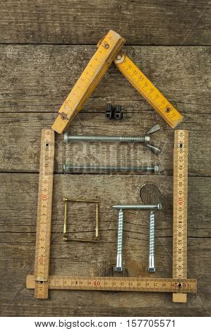 Plans to build a house. Rustic wooden background. Tools for builders. Architect designing a house for a young family. House from nails and screws. Needed for building. Ideas about building a house.