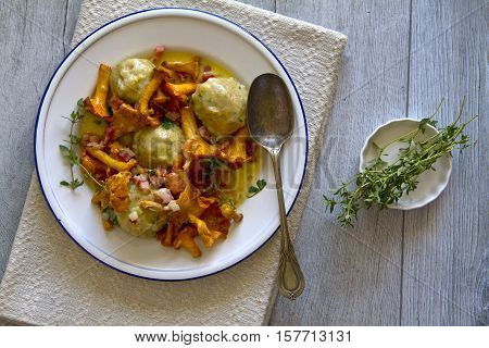 Bread dumplings with chanterelles on a plate with fresh Majoram
