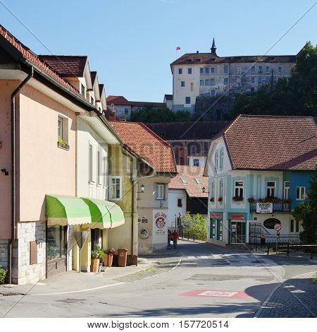 Gmina Škofja Loka, Škofja Loka Slovenia - September 25 2016: Capuchin market. In the background on the hill is visible the Bishops Castle, now the Loka Museum. Two people are visible on the street, also visible is the entrance to the Capuchin Bridge.