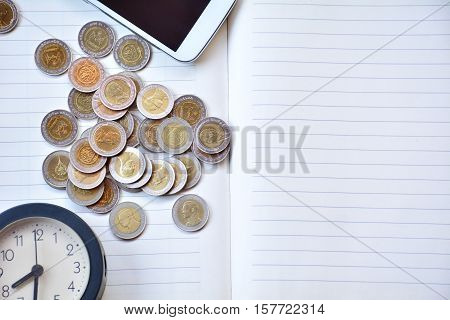 Coins clock and smart-phone on the note book.