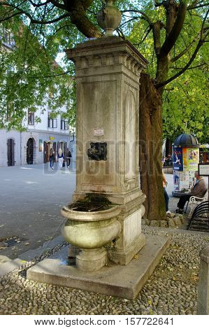 Gmina Škofja Loka, Škofja Loka Slovenia - September 25 2016: Mestni trg (City Square). Stone fountain built in 1883. Water pours from the fountain after touching the hand.