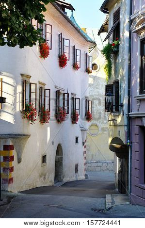 Gmina Škofja Loka, Škofja Loka Slovenia - September 25 2016: old town Mestni trg (City Square). Typical buildings, windows decorated with flowers. In the background there is Parish Church.
