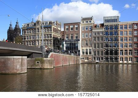 AMSTERDAM, NETHERLANDS - MAY 3, 2016: Beautiful view of the bridge and typical dutch buildings on Damrak canal of Amsterdam, Netherlands