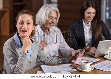 Get what you want. Three female ambitious colleagues enjoying their productive workday while sitting in an office and making project.