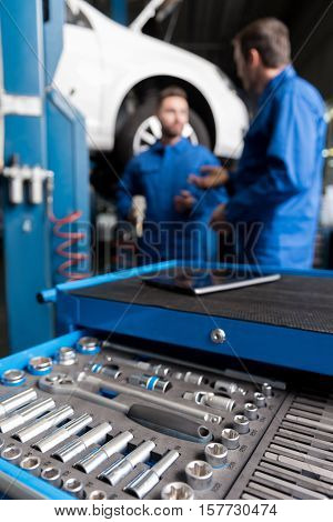 Necessary equipment. Selective focus of set with tools with professional mechanics working in the background