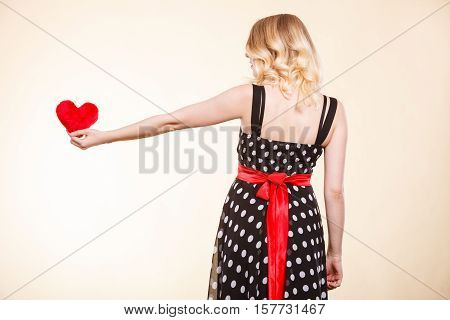 Valentine day gift proof of love romantic present concept. Woman in retro polka dot dress holding small furry red heart