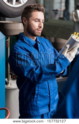 Everything is ok. Pleasant serious man holdign oil filter and examining it while reparing car