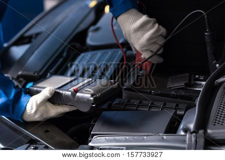 Look it correctly. Close up of special device in hands of professional mechanic checking car engine while conducting car meintenance