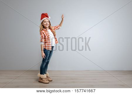 My little toy. Cheerful cute smiling girl ringing the bell and looking at you while celebrating New Year