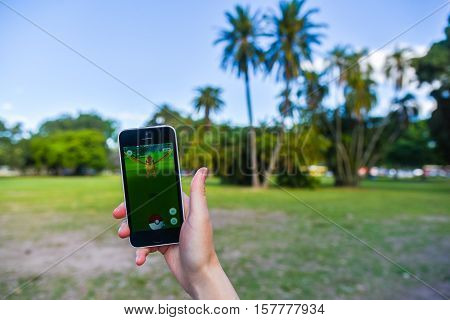 Buenos Aires, Argentina - Nov 11, 2016: Apple iPhone 5c held in one hand showing its screen with Pokemon Go application. Palms on the background.
