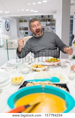 Family gathering eating meal around kitchen table