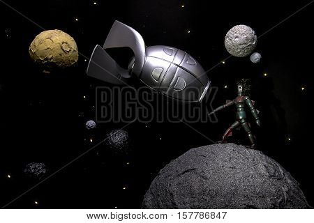 Space explorer. Model showing an alien life form and a space rocket amongst planets and stars in space. A retro B movie style image with many connotations relating to astronomy and space exploration.