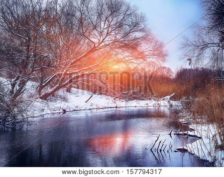 Winter landscape by a river in the sunset. Mirror reflection