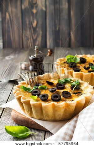 Homemade quiche tart with chicken eggplant olives and cheese on old wooden background. Selective focus.