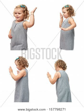 Young little girl with curly hair in gray dress standing and giving high five over isolated white background