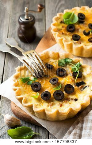 Homemade quiche tart with chicken eggplant olives and cheese on old wooden background. Selective focus.