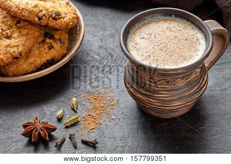 Masala pulled tea chai latte traditional hot Indian sweet milk spiced drink, ginger, cinammon sticks, fresh spices blend, anise organic infusion healthy wellness beverage in rustic clay cup