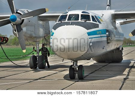 Vasilkov Ukraine - April 24 2012: Ukraine Air Force Antonov An-26 cargo plane is preparing to start the engines with the starter vehicle on the airfield