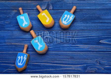 Dreidels for Hanukkah on blue wooden table