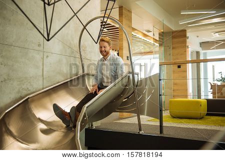 Handsome man descending on a toboggan in the office.