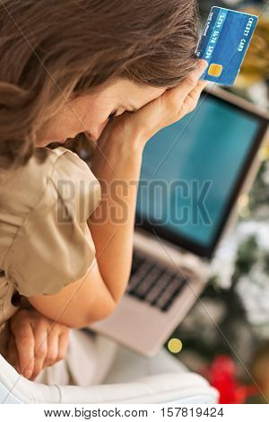 Stressed Young Woman With Credit Card And Laptop In Front Of Christmas Tree
