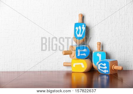 Dreidels for Hanukkah on wooden table against light textured wall