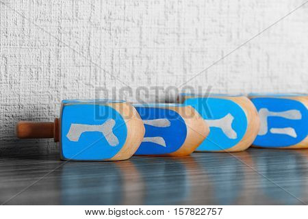 Dreidels for Hanukkah on wooden table against light textured wall