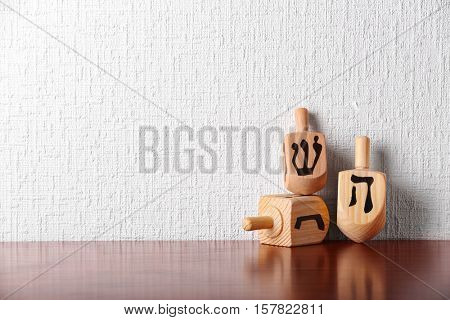 Dreidels for Hanukkah on wooden table against light textured wall