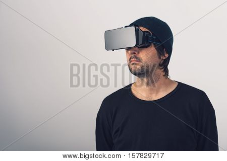 Male actor immersed in experience of virtual reality environment wearing vr goggles augmented-reality headset and enjoying 3d cyberspace multimedia content.