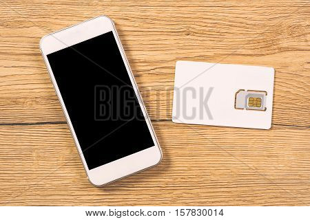 Smartphone electronics device and blank SIM card as copy space on office table top view