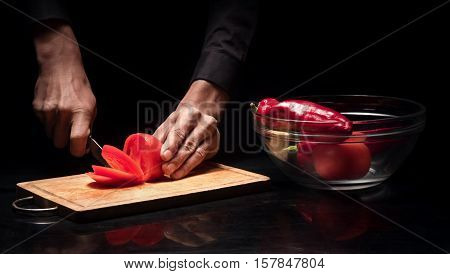 Fresh vegetables. Close up of young mans hands chopping juicy tomato while cooking and working as a chef in restaurant.